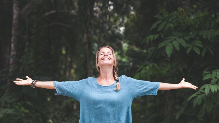 Woman with her arms outstretched in nature thinking about the meaning of lent