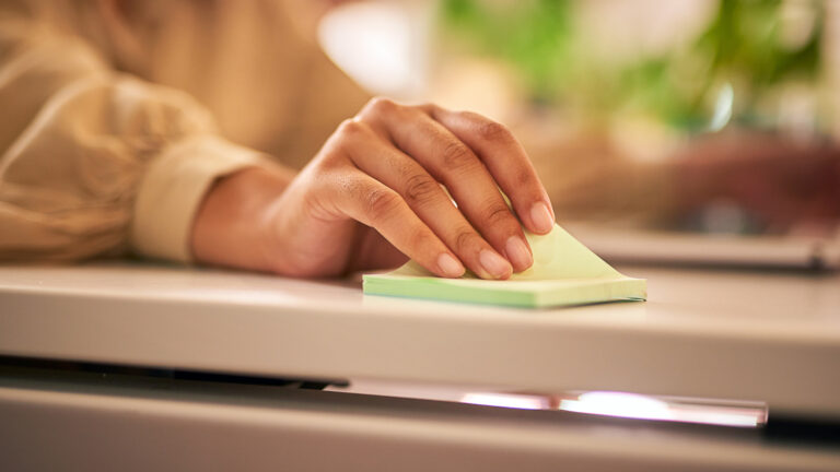 Woman's hand pulling up a sticky note for her new habits