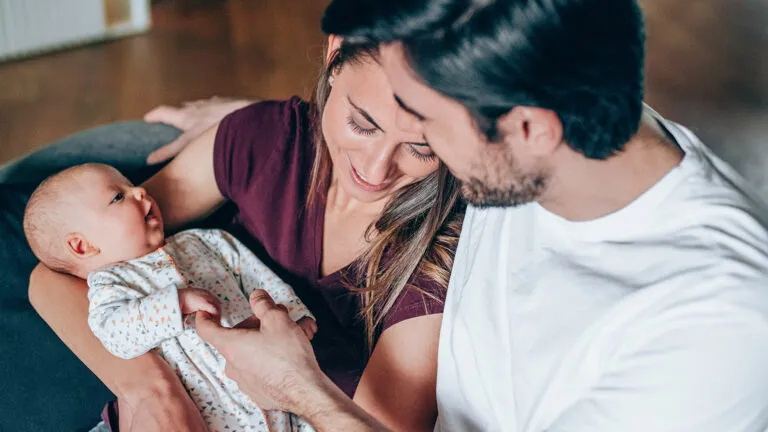 Young couple embracing their newborn baby; Getty Images