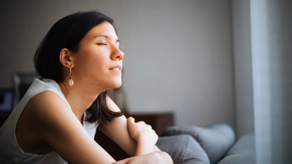 woman on a sofa praying by the window