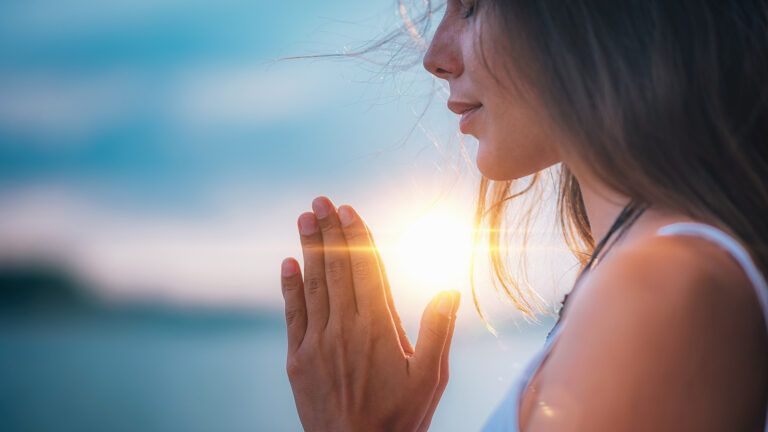 A woman prays at sunrise; Getty Images