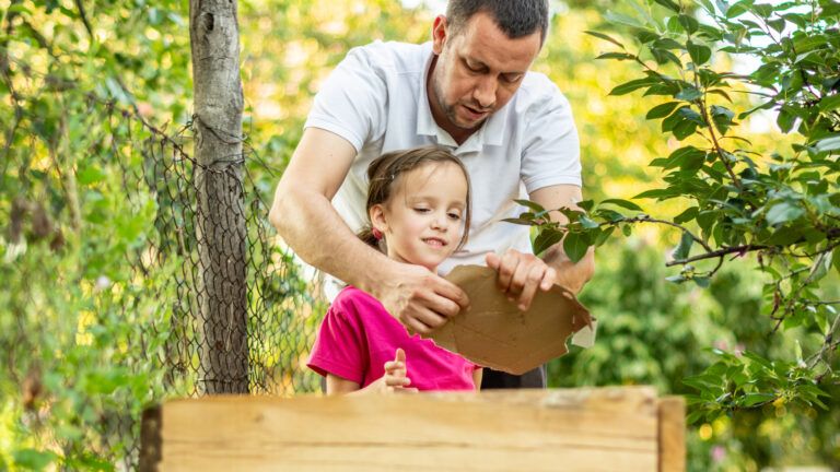 Father and daughter help the environment by composting