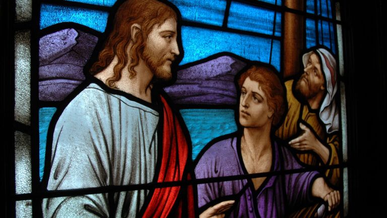 Stained glass depiction of disciples listening to Jesus