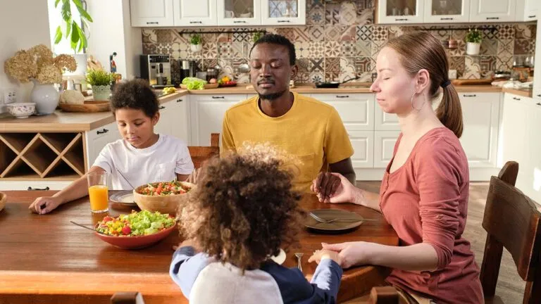 Family praying together before a meal for their lent family activity