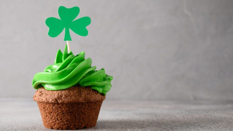 Cupcake decorated with green icing and a shamrock
