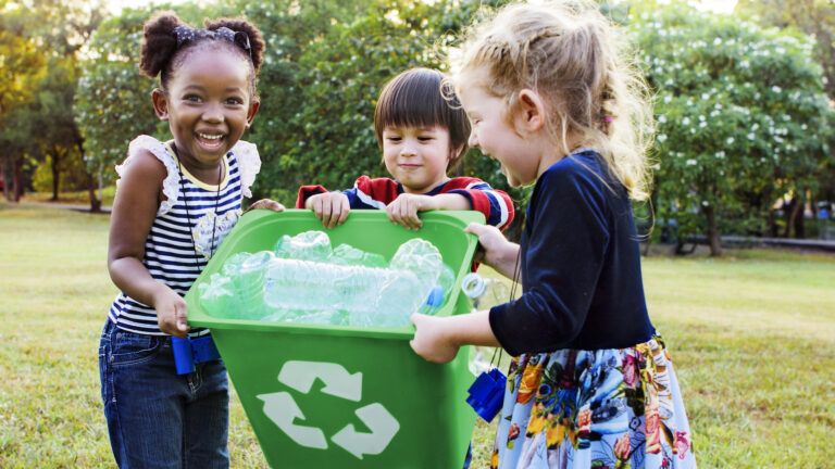 Kids practice a green lent by cleaning up a park with a recycling can