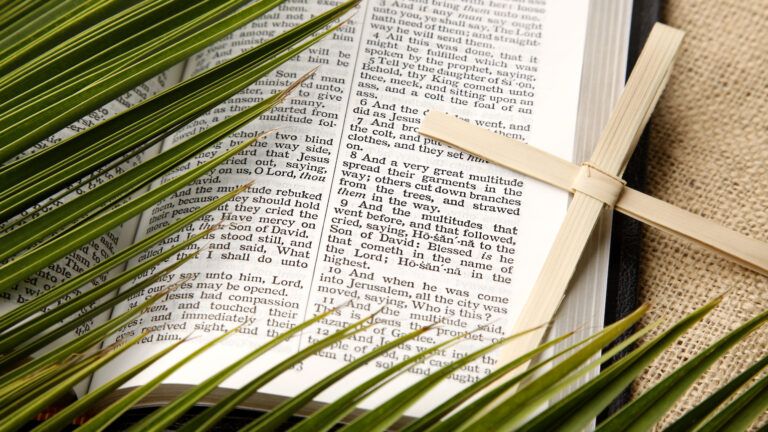 Palm Sunday in the Bible as depicted by palms and cross laid across the Bible.