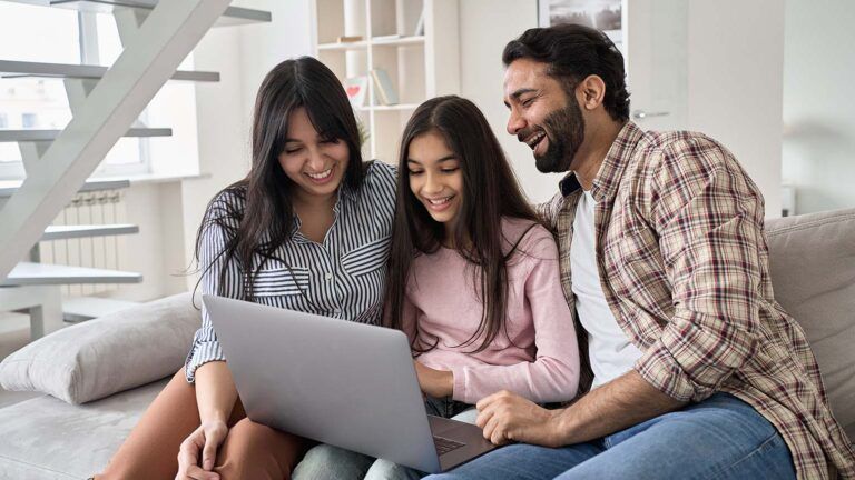 Parents on the couch with their teen daughter making their lent goals on a laptop