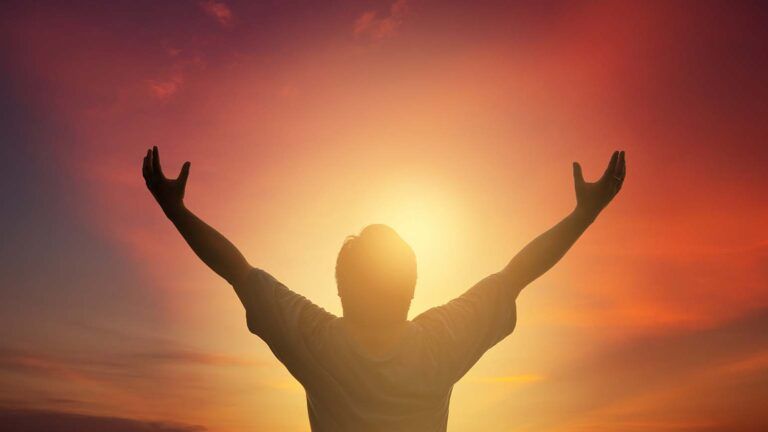 Person with arms raised at sunset feeling accomplished after following their lent plan
