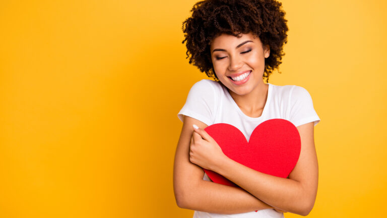 Happy, single woman holding a heart on Valentine's Day.