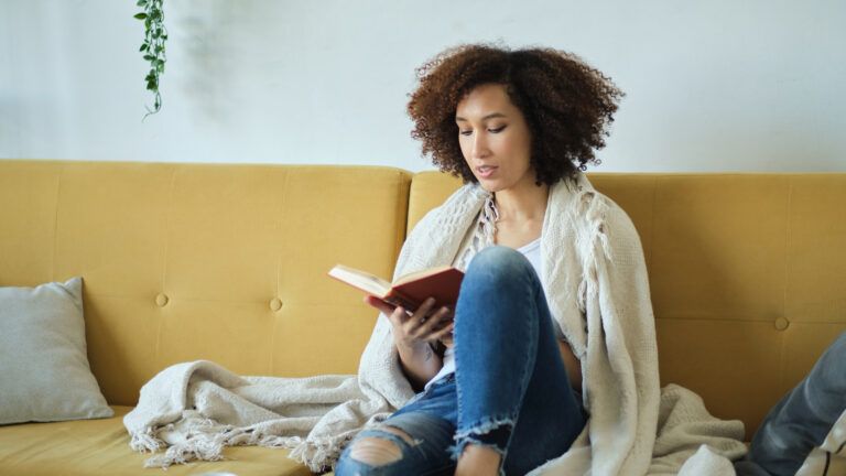 Woman reading a book on the couch for her green Lent practice