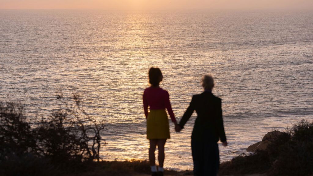 Two people standing on a beach.