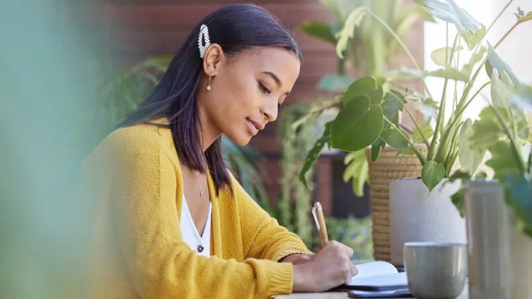 Young woman writing down her Lent goals; Getty Images