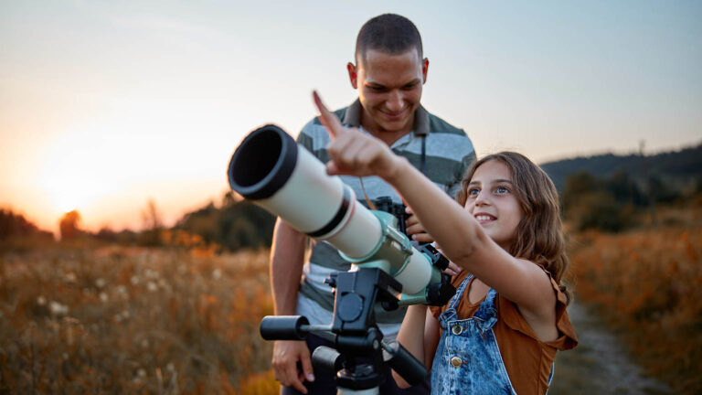 Father and daughter stargazing together with a telescope for their spring activity