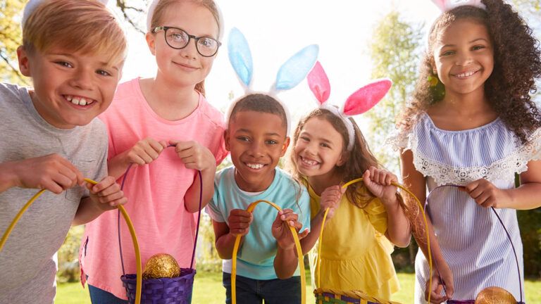 Five kids doing the tradition of an Easter egg hunt with baskets