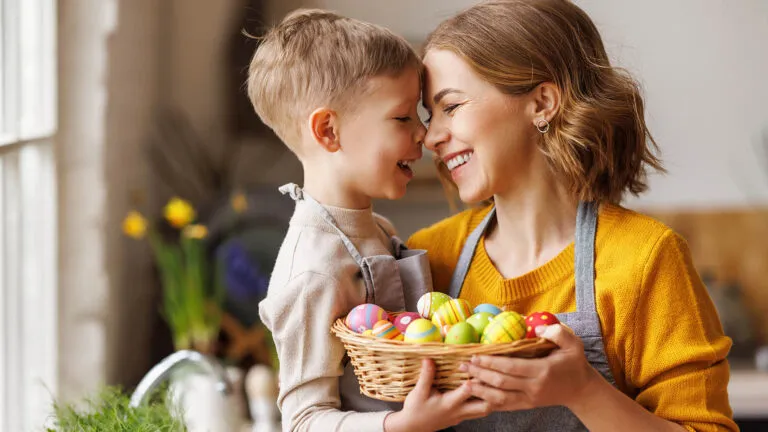 Mother and son hold Easter eggs in a basket for their Easter tradition