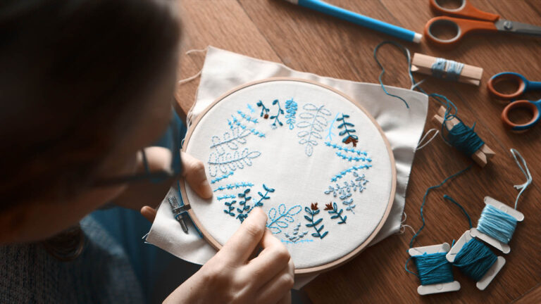 Woman taking up the spring activity of embroidery with blue thread