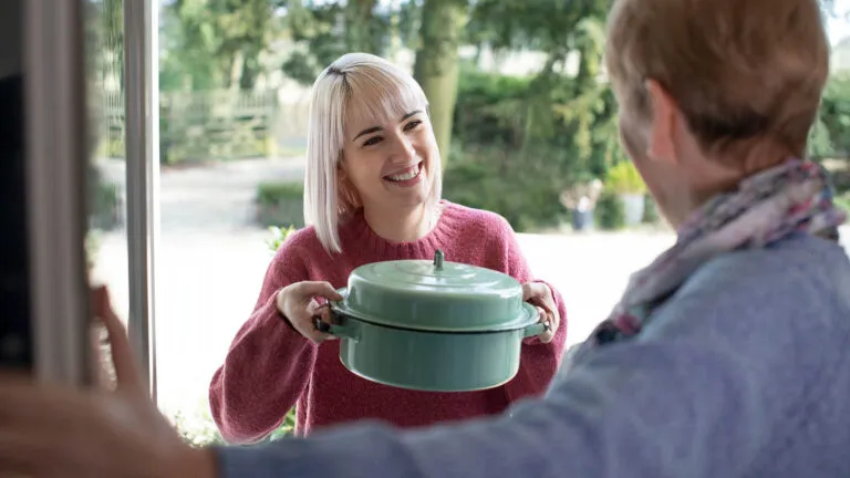 Young woman doing her Easter tradition of cooking for her elderly neighbor